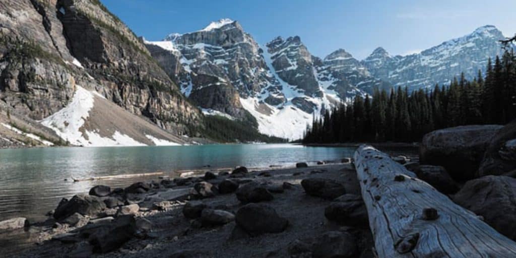 Scenic view of a mountain lake surrounded by towering snow-capped peaks and dense evergreen forests, perfect for destination wedding photography.